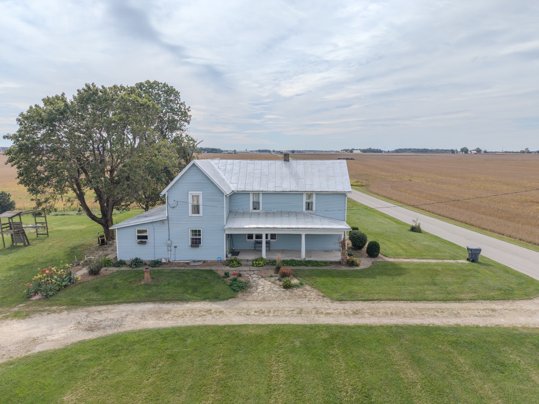 Side aerial view of a rural home and surrounding fields